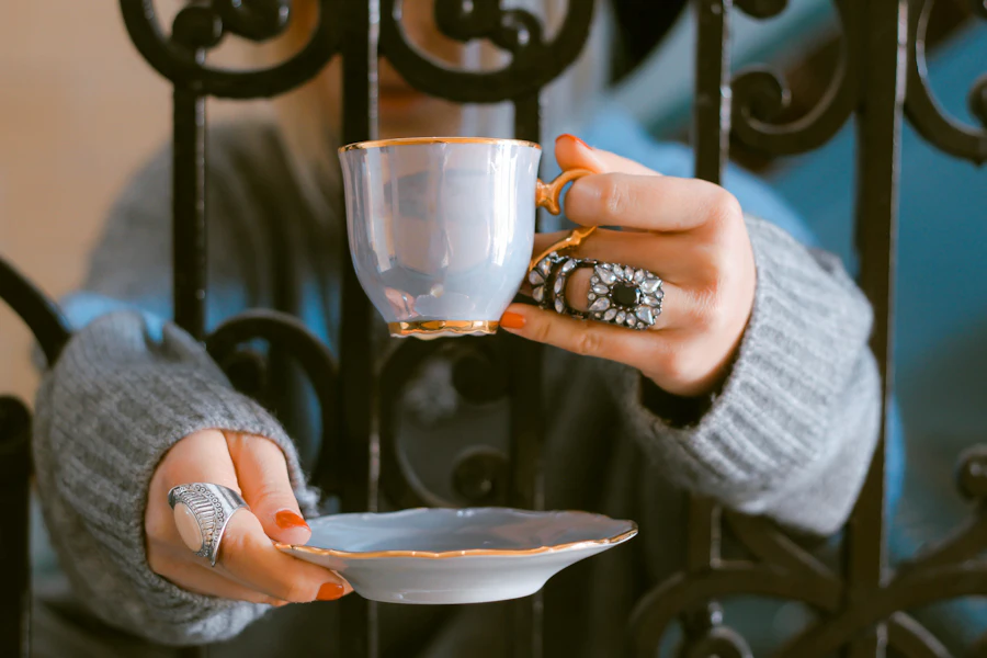 Hands gently cradling a porcelain teacup and saucer