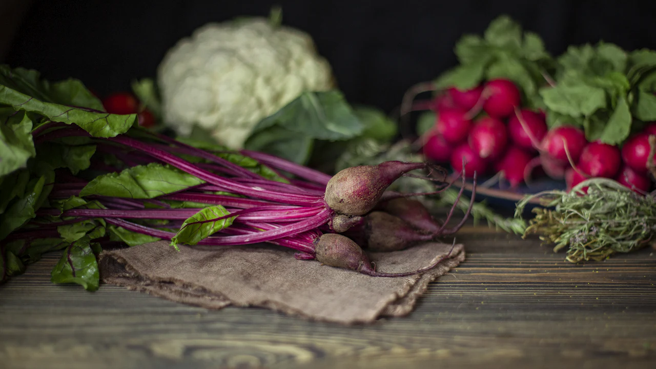 Fresh whole vegetables on a dark wooden table in natural light
